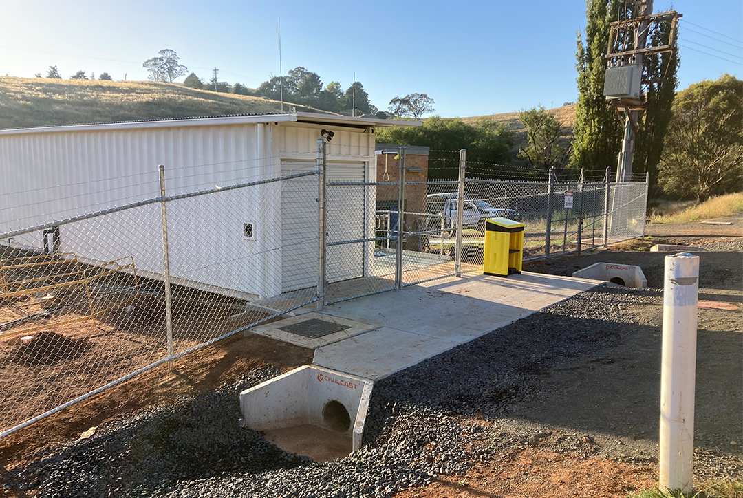 The Potassium Permanganate dosing plant building is nearing completion. The image shows the fenced, constructed building with a background of rolling hills.